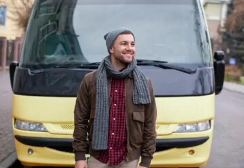 A man smiling in front of a van taxi in Cusco